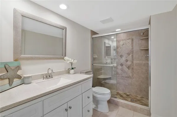 a bathroom with a shower sink vanity mirror and toilet