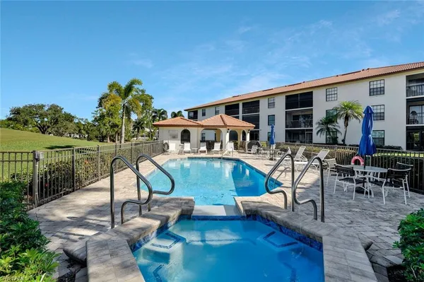 a view of a swimming pool with chairs and table in a patio