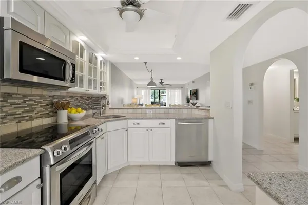 a kitchen with stainless steel appliances granite countertop a sink a stove top oven a chimney cabinets and a counter top space