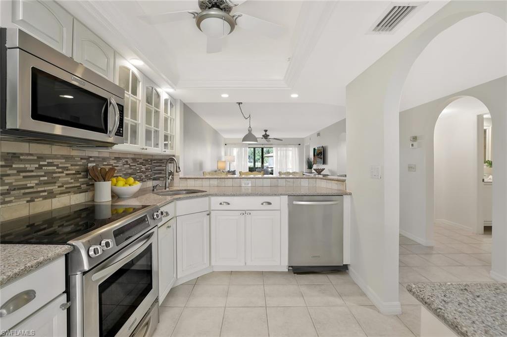 601 Augusta Boulevard, Unit 6014 Naples, FL 34113 - Photo 3 of 31 a kitchen with stainless steel appliances granite countertop a sink a stove top oven a chimney cabinets and a counter top space