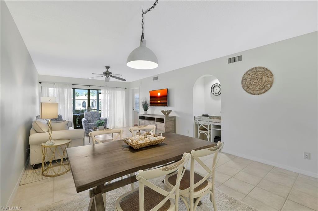 601 Augusta Boulevard, Unit 6014 Naples, FL 34113 - Photo 6 of 31 a view of a dining room and livingroom with furniture wooden floor a rug and a clock
