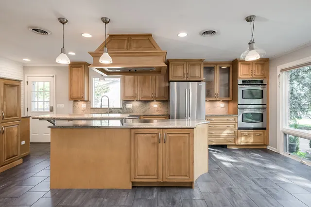 a kitchen with stainless steel appliances granite countertop a sink a stove and a wooden floors
