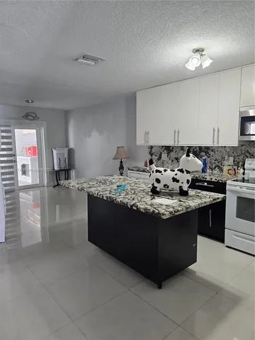 a kitchen with granite countertop a sink stove and cabinets