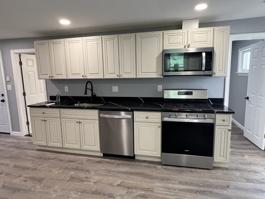 99 Chelsea Street, Unit 3 Boston, MA 02128 - Photo 3 of 10 a kitchen with granite countertop white cabinets and stainless steel appliances