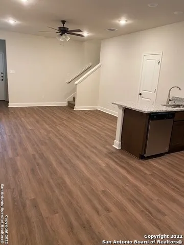 an empty room with wooden floor and a ceiling fan