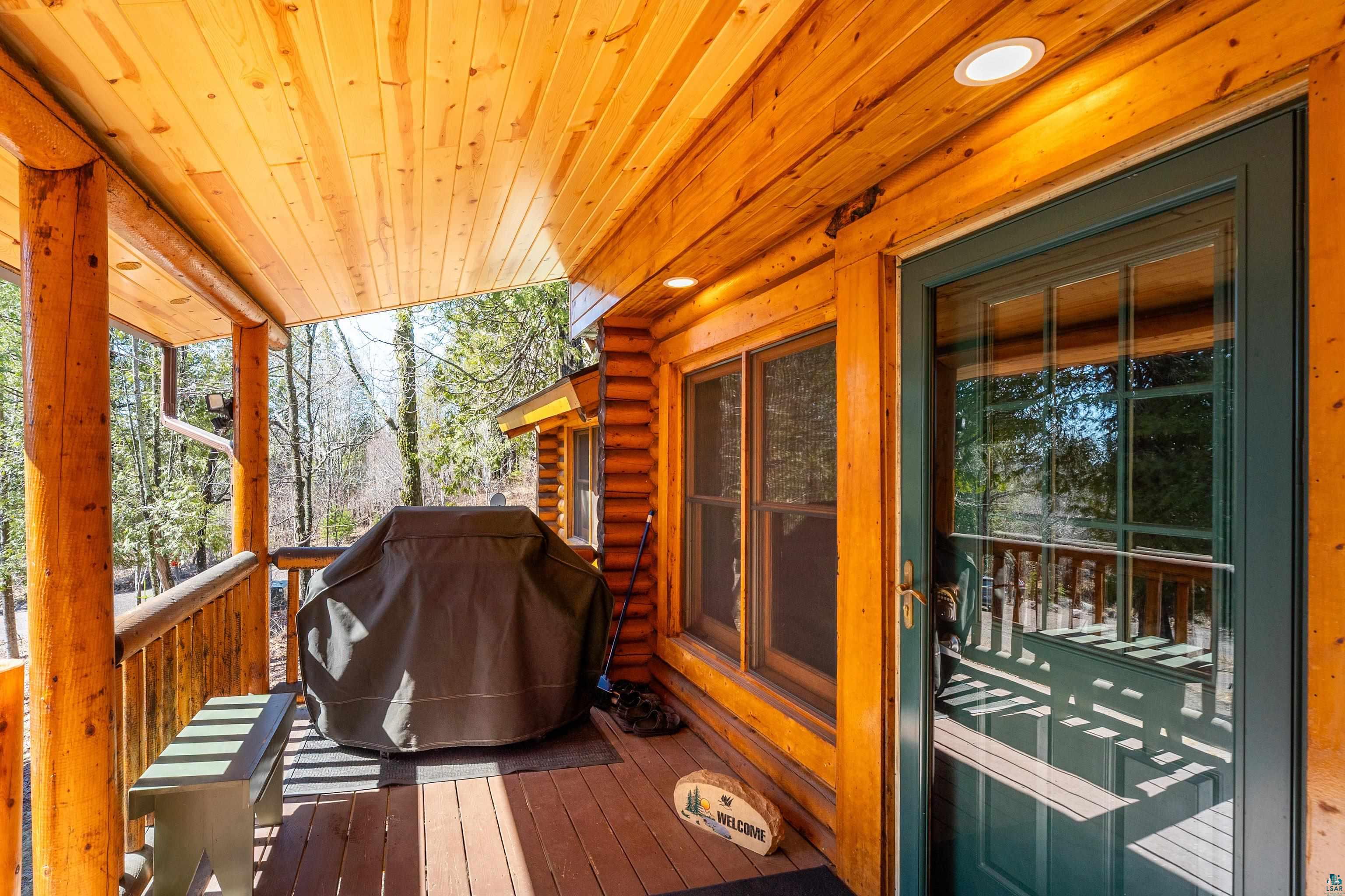 2659 Ridgeview Drive Two Harbors, MN 55616 - Photo 11 of 56 Inviting covered porch featuring natural wood log construction, wood-finish flooring, a wood-paneled ceiling with recessed lighting, and a dark green entry door with glass panels