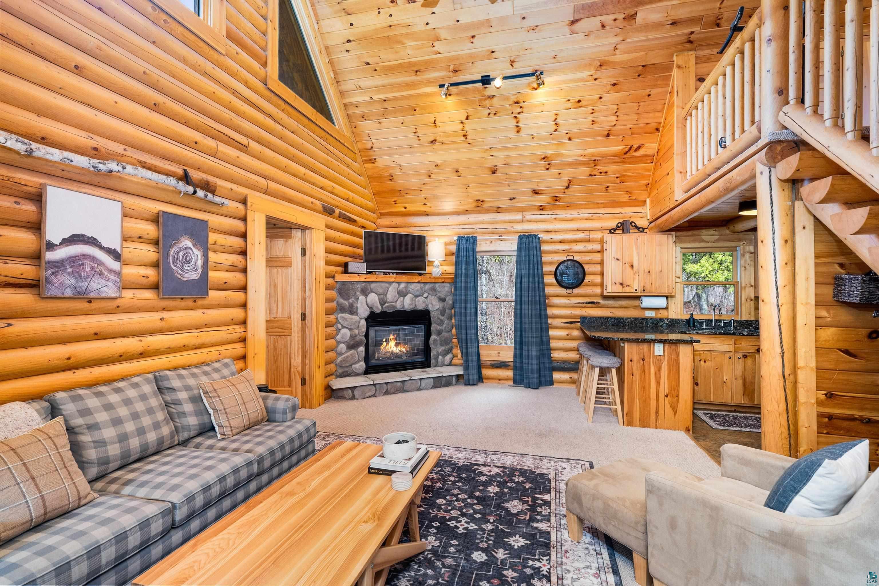 2659 Ridgeview Drive Two Harbors, MN 55616 - Photo 14 of 56 Vaulted wood-paneled ceiling showcasing a stone-faced fireplace, a built-in wet bar, a wood-paneled door, and a loft space with wood railing