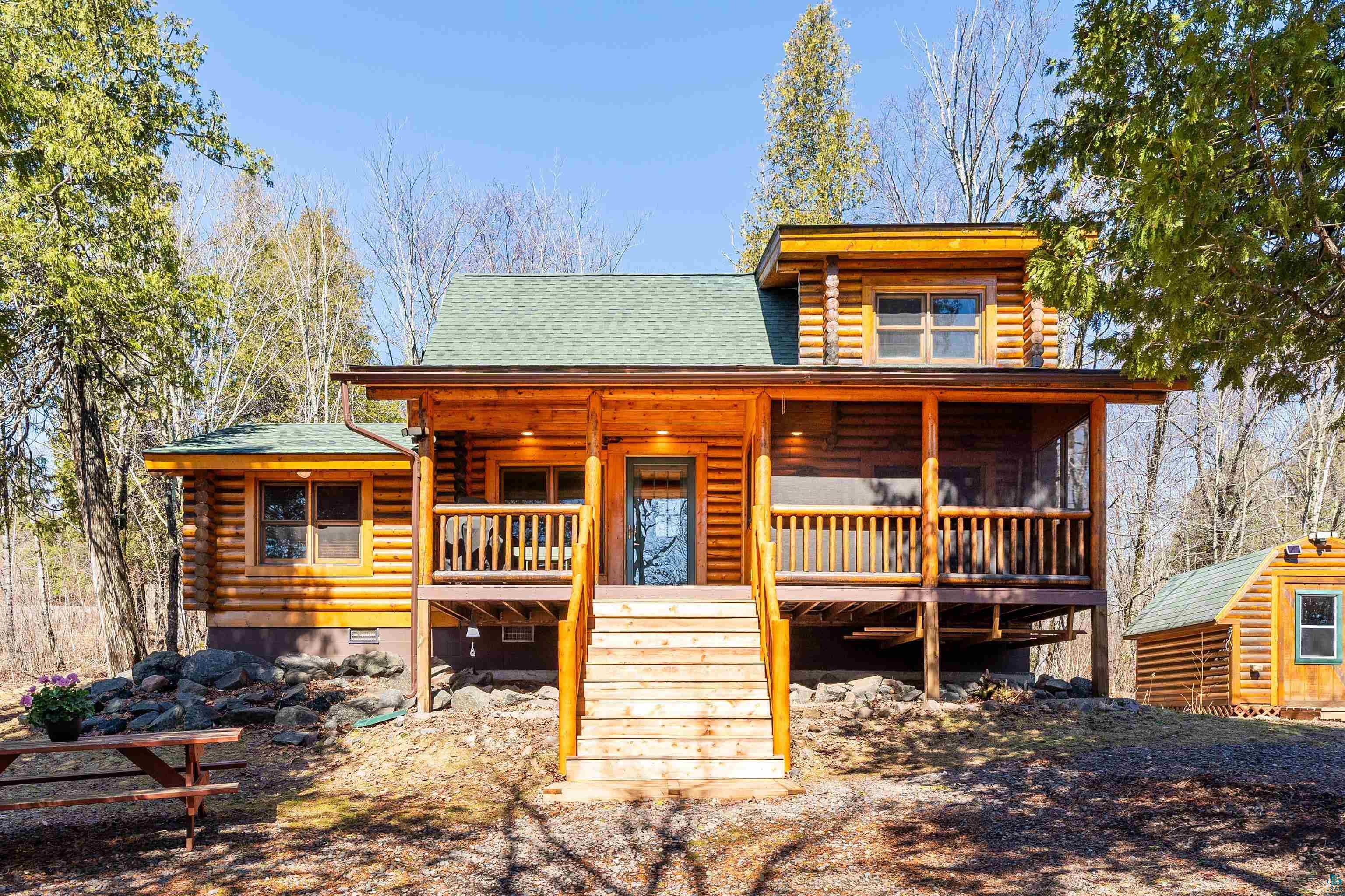 2659 Ridgeview Drive Two Harbors, MN 55616 - Photo 2 of 56 Log cabin exterior featuring a covered porch, screened-in deck, green shingle roofing, and a prominent wood staircase entrance