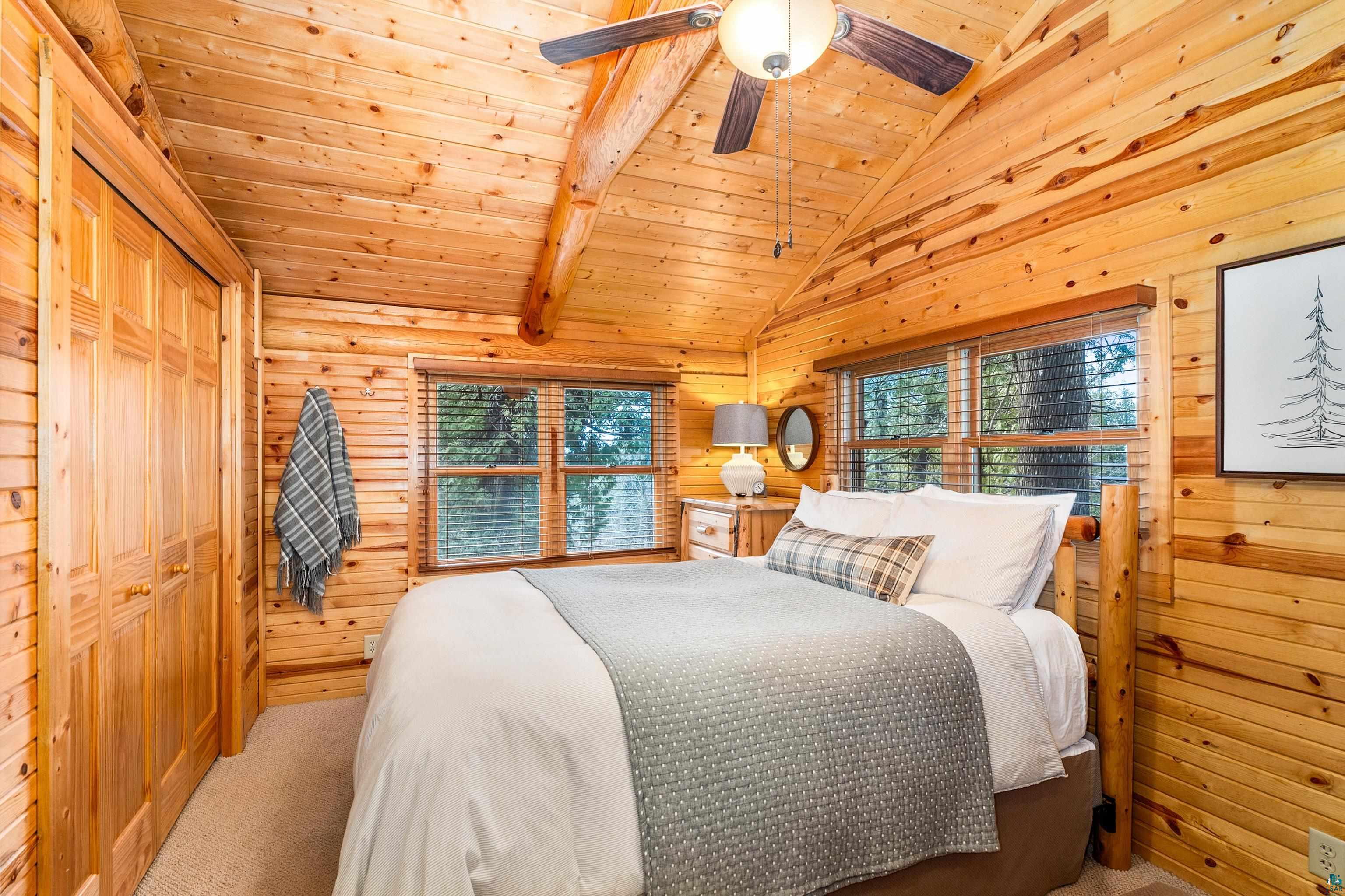 2659 Ridgeview Drive Two Harbors, MN 55616 - Photo 23 of 56 Vaulted wood plank ceiling with exposed log beams and a ceiling fan light fixture