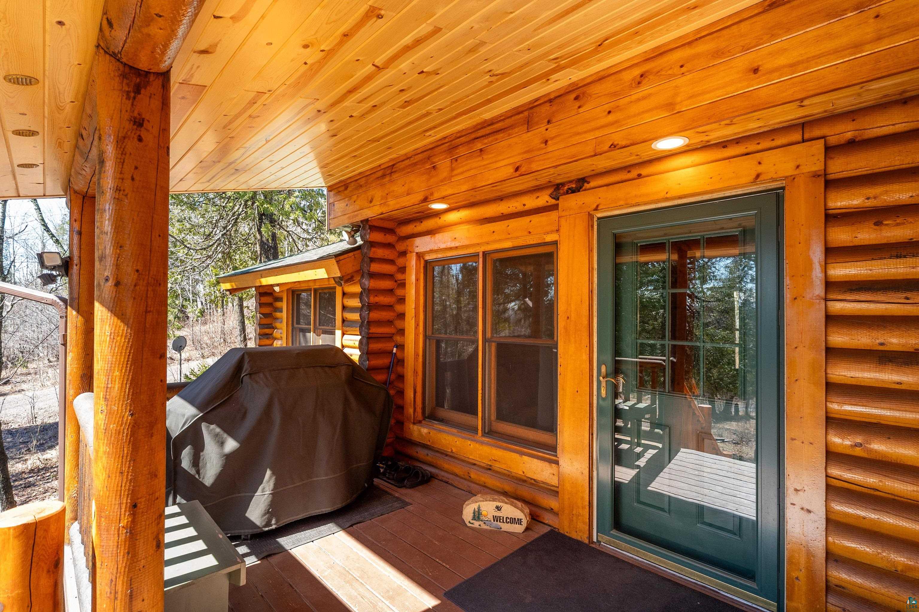 2659 Ridgeview Drive Two Harbors, MN 55616 - Photo 7 of 56 Covered wood-finish porch featuring exposed log pillars, a tongue-and-groove ceiling with recessed lighting, and a dark green storm door