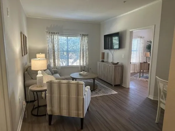 a living room with furniture a flat screen tv and wooden floor
