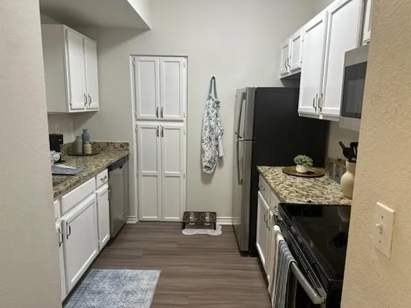 a kitchen with granite countertop a refrigerator stove and sink