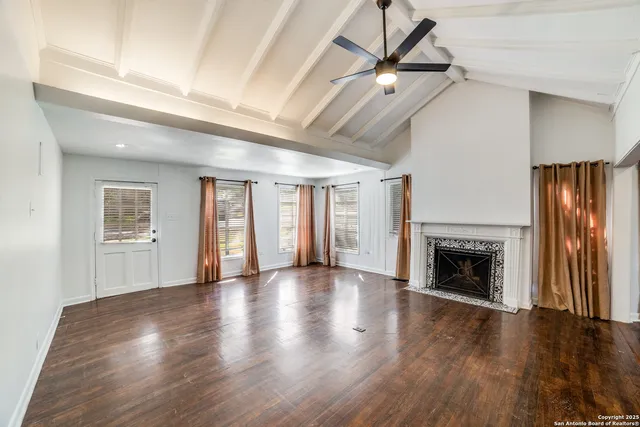 an empty room with windows fireplace and a ceiling fan