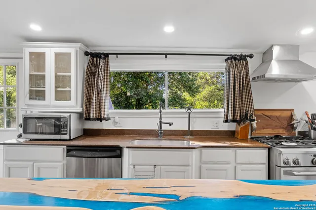 a kitchen with stainless steel appliances granite countertop a stove a sink and a granite counter tops with a large window