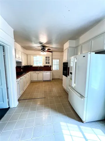 a large white kitchen with cabinets and a refrigerator