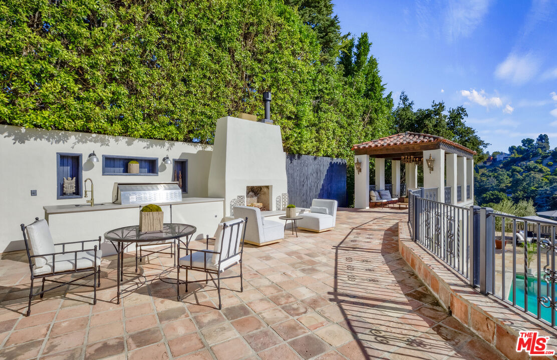 4565 Dundee Drive Los Angeles, CA 90027 - Photo 25 of 42 a view of a patio with a table and chairs under an umbrella with wooden fence