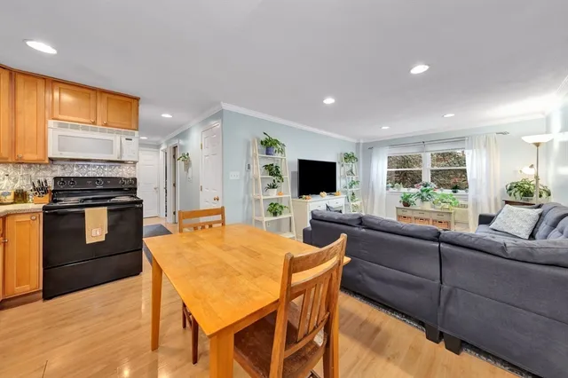 a kitchen with stainless steel appliances kitchen island granite countertop a stove a sink dishwasher a dining table and chairs with wooden floor