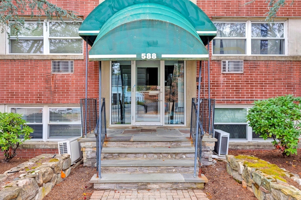 588 Main Street, Unit 3C Stoneham, MA 02180 - Photo 2 of 24 a view of a brick house with plants and large tree