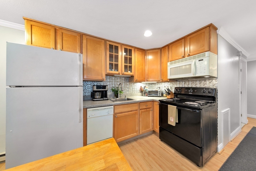 588 Main Street, Unit 3C Stoneham, MA 02180 - Photo 9 of 24 a kitchen with stainless steel appliances granite countertop a refrigerator a stove a sink and a microwave