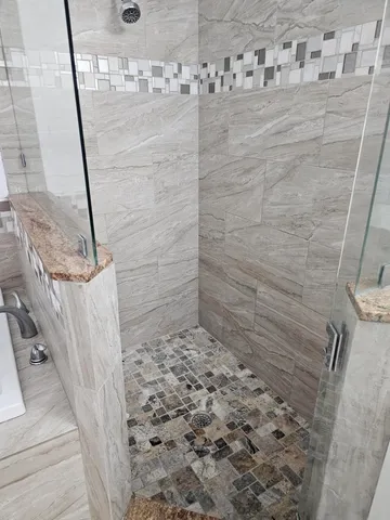 a bathroom with a granite countertop sink a toilet a mirror and shower