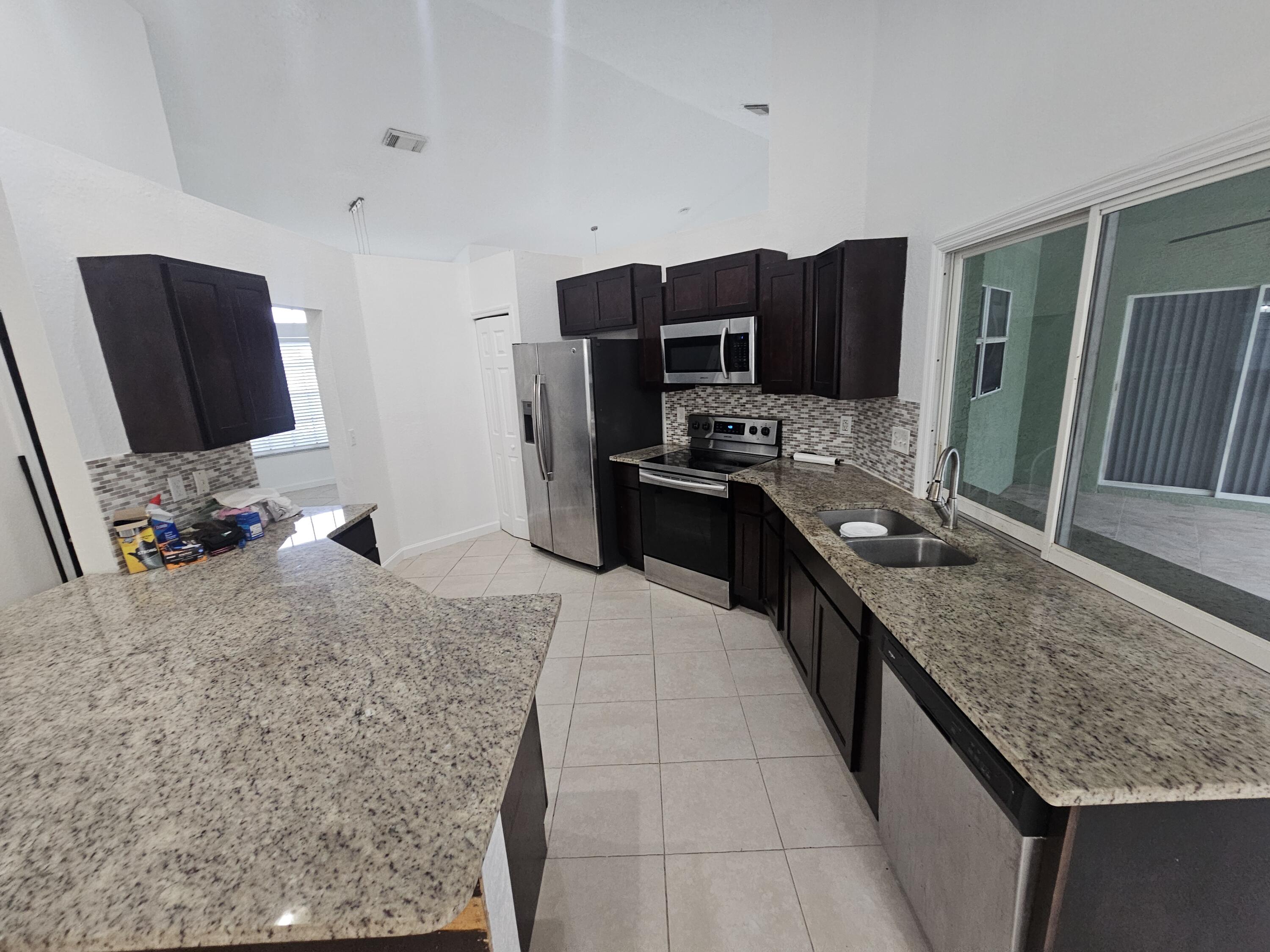 3215 Southeast Pinto Street Port St. Lucie, FL 34984 - Photo 20 of 34 a kitchen with kitchen island granite countertop a sink appliances and cabinets