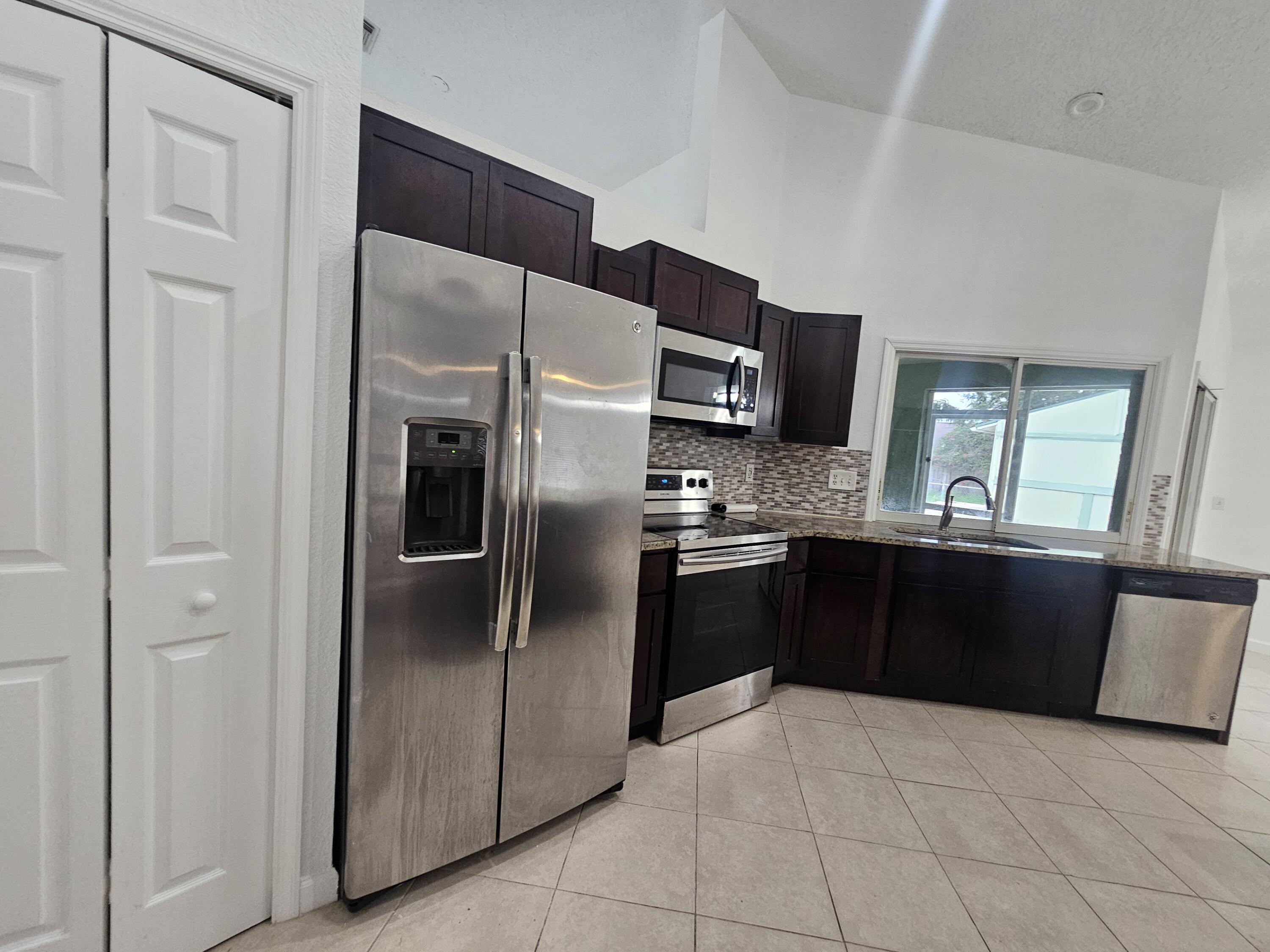 3215 Southeast Pinto Street Port St. Lucie, FL 34984 - Photo 22 of 34 a kitchen with a refrigerator sink and microwave