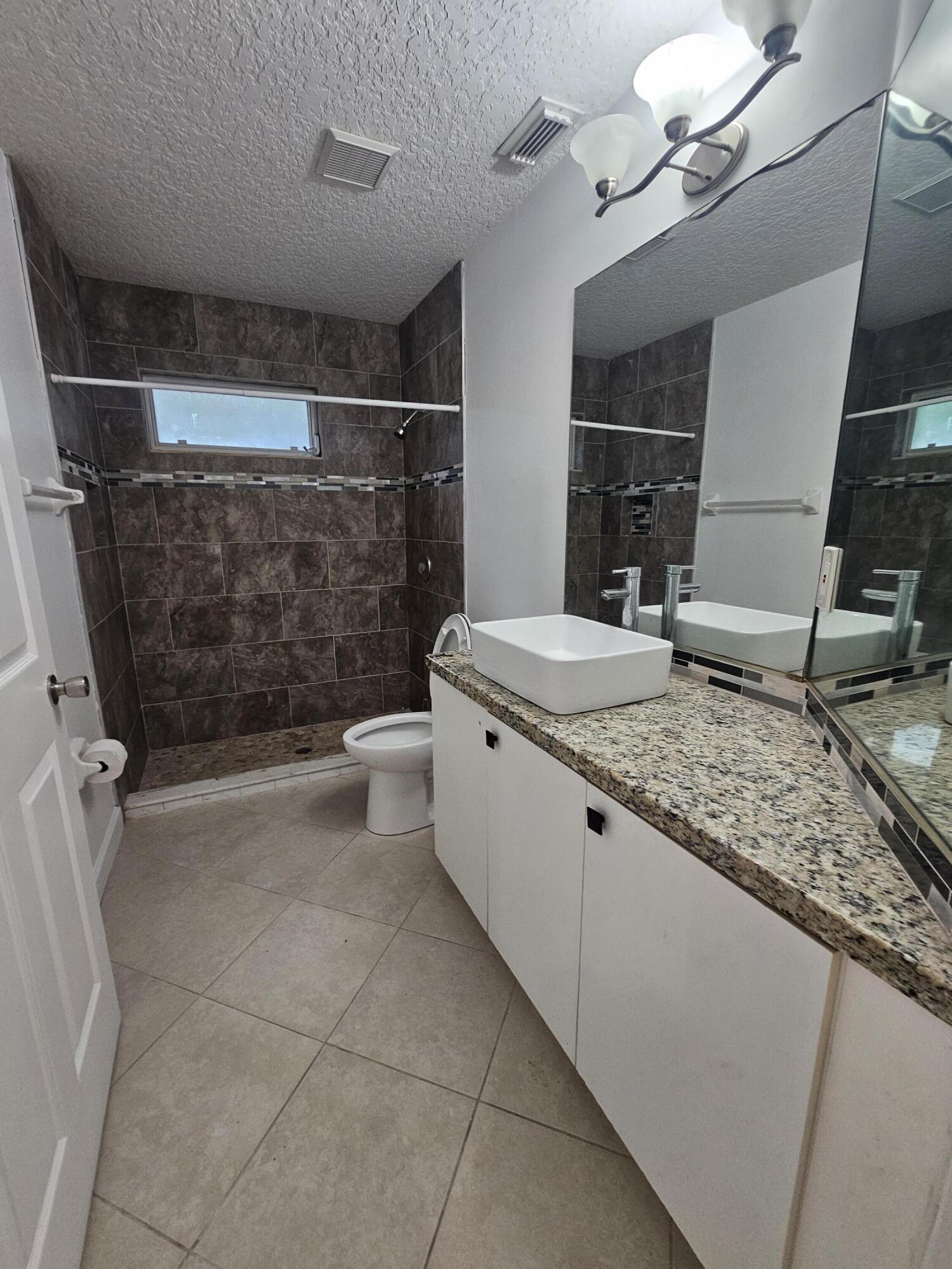 3215 Southeast Pinto Street Port St. Lucie, FL 34984 - Photo 24 of 34 a bathroom with a granite countertop sink a toilet and shower