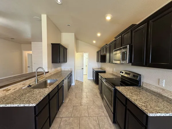 a large kitchen with granite countertop stainless steel appliances and a sink
