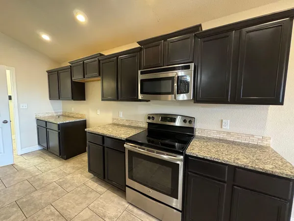 a kitchen with stainless steel appliances granite countertop a stove microwave and refrigerator