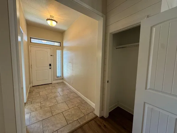 a view of a hallway with wooden floor and closet area