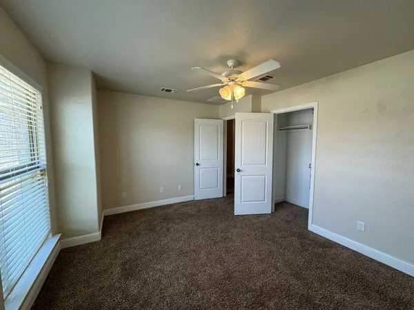 an empty room with a ceiling fan and a window