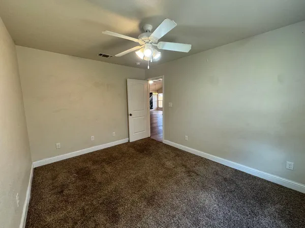 an empty room with a ceiling fan and a window