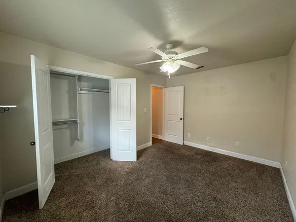 an empty room with closet and windows