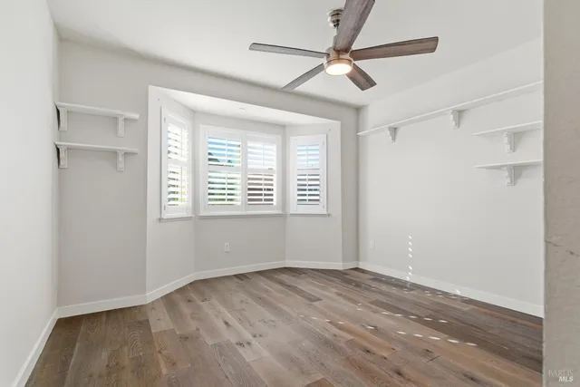 a view of empty room with wooden floor and fan