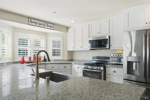 a kitchen with stainless steel appliances granite countertop a stove a sink dishwasher a refrigerator and a microwave