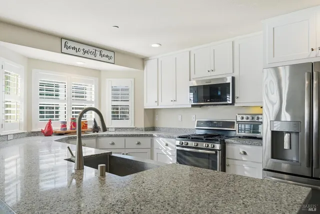 a kitchen with stainless steel appliances granite countertop a stove a sink dishwasher a refrigerator and a microwave