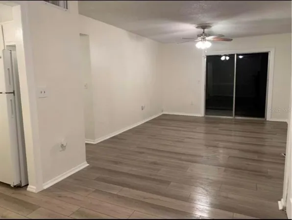 an empty room with wooden floor fan and window