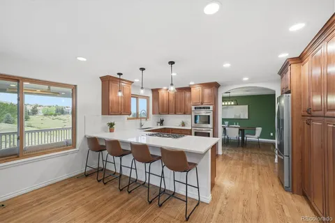 a kitchen with stainless steel appliances a dining table chairs and wooden floor