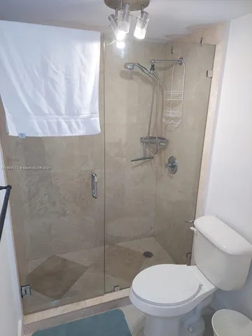 a white toilet sitting next to a shower