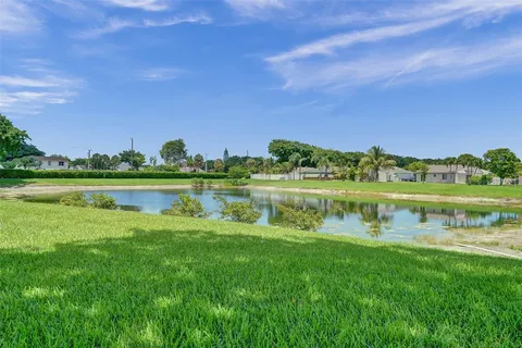 a view of a lake with a yard and large trees