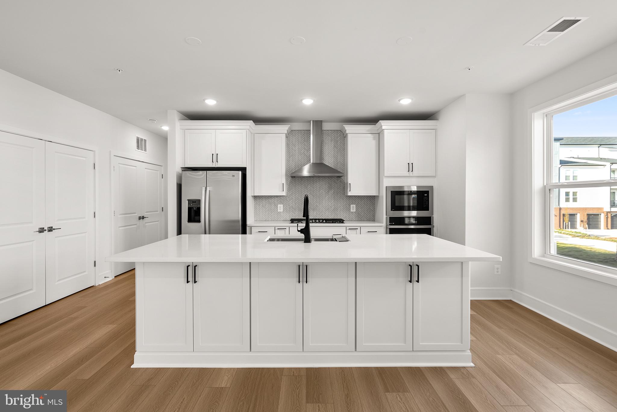 a large white kitchen with lots of counter space a sink appliances and cabinets