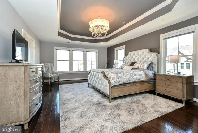 a spacious bedroom with a bed a chandelier and dresser