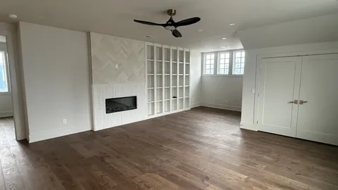 an empty room with wooden floor a ceiling fan and windows