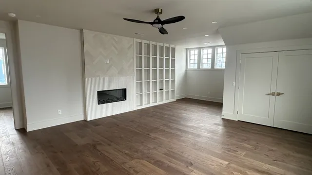 an empty room with wooden floor a ceiling fan and windows