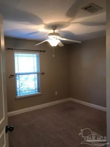 en empty room with windows and fan