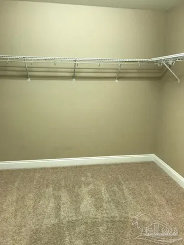 a view of an empty room with window and chandelier fan