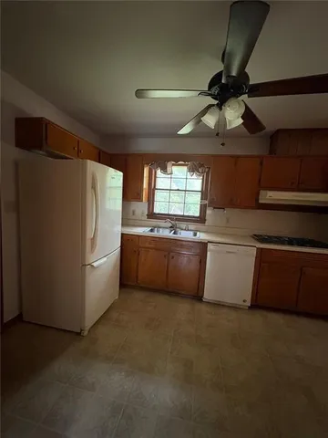 a kitchen with stainless steel appliances a refrigerator a sink a stove and white cabinets