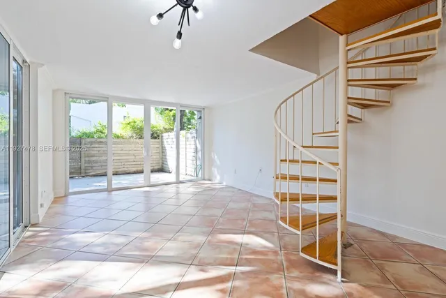 a view of an empty room with stairs and chandelier fan