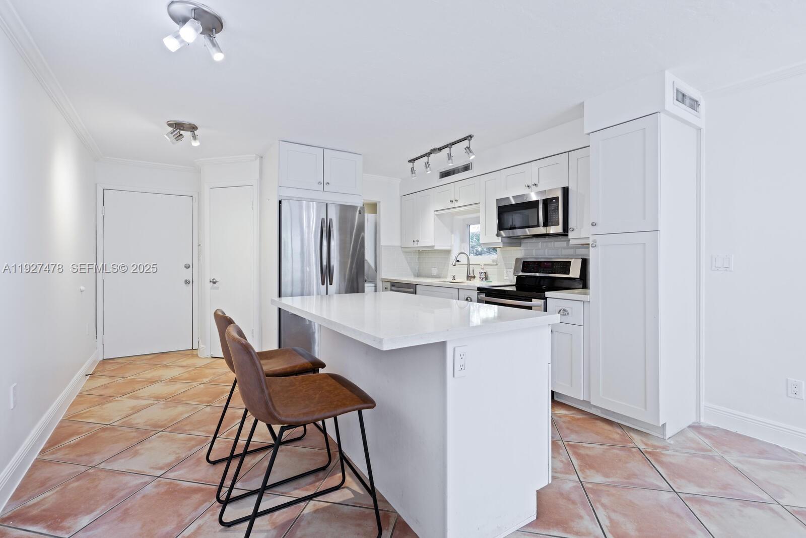 3028 Center Street, Unit 3028 Miami, FL 33133 - Photo 8 of 24 a kitchen with stainless steel appliances kitchen island granite countertop a refrigerator and a stove top oven