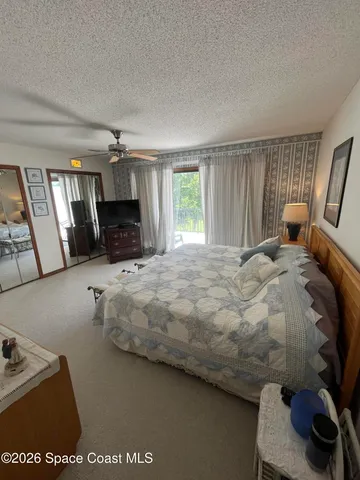 a large bed sitting in a bedroom next to a window and a flat screen tv